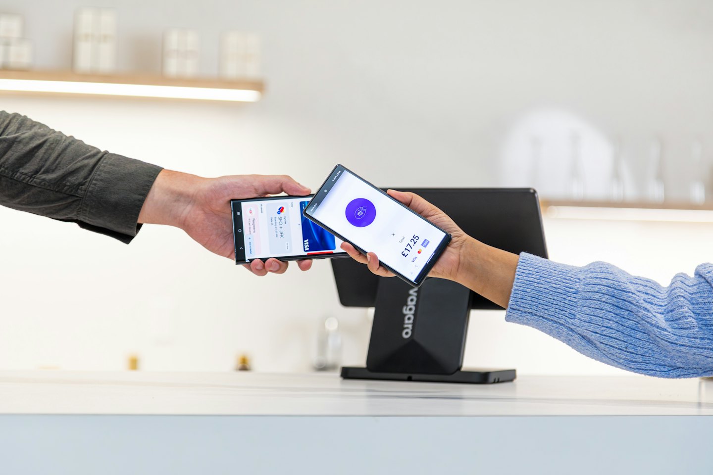 Zwei Personen tätigen kontaktlos eine digitale Zahlung per Smartphone.